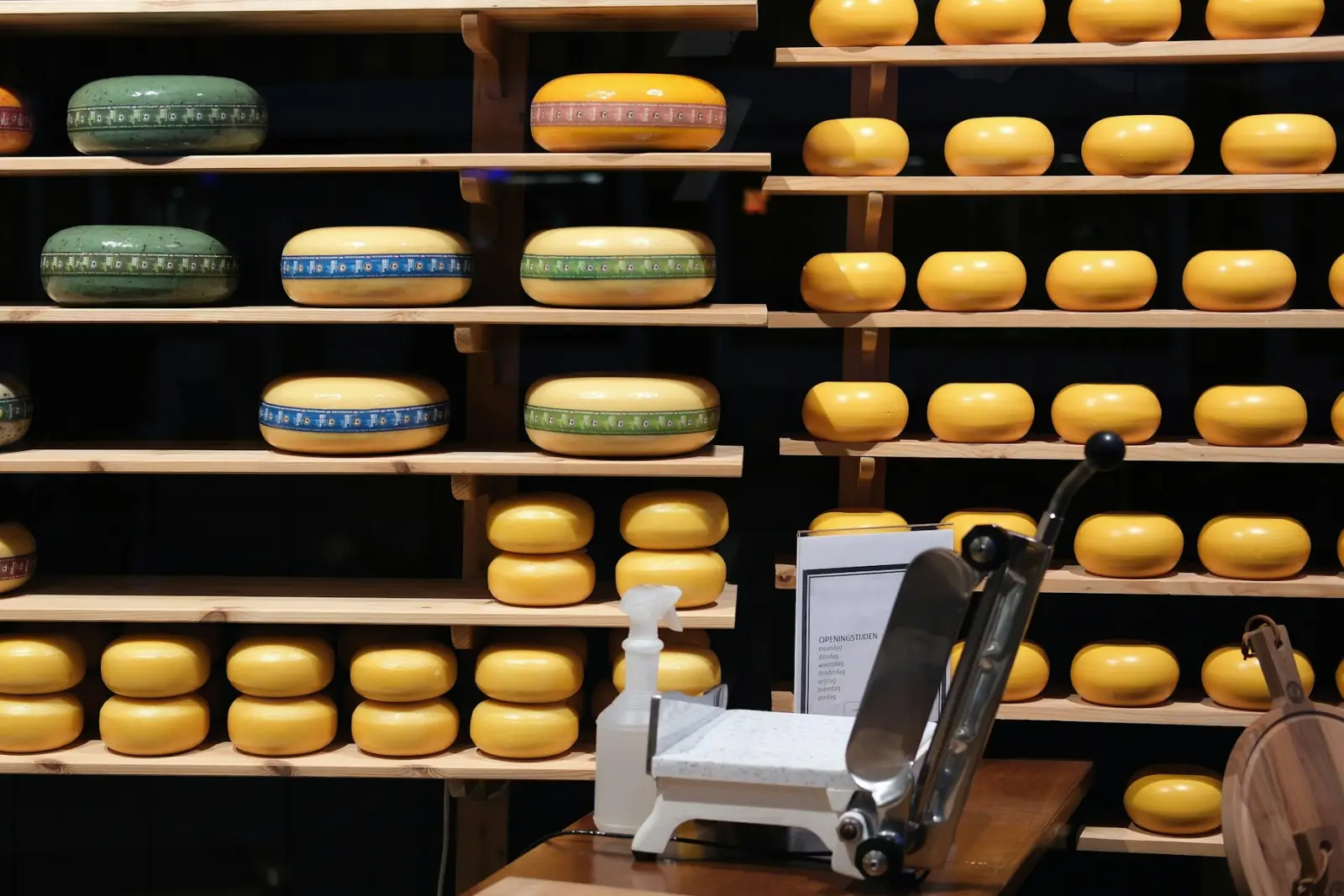 Kaaswinkel met goudse kazen op houten schappen en een kaasschaaf op de toonbank